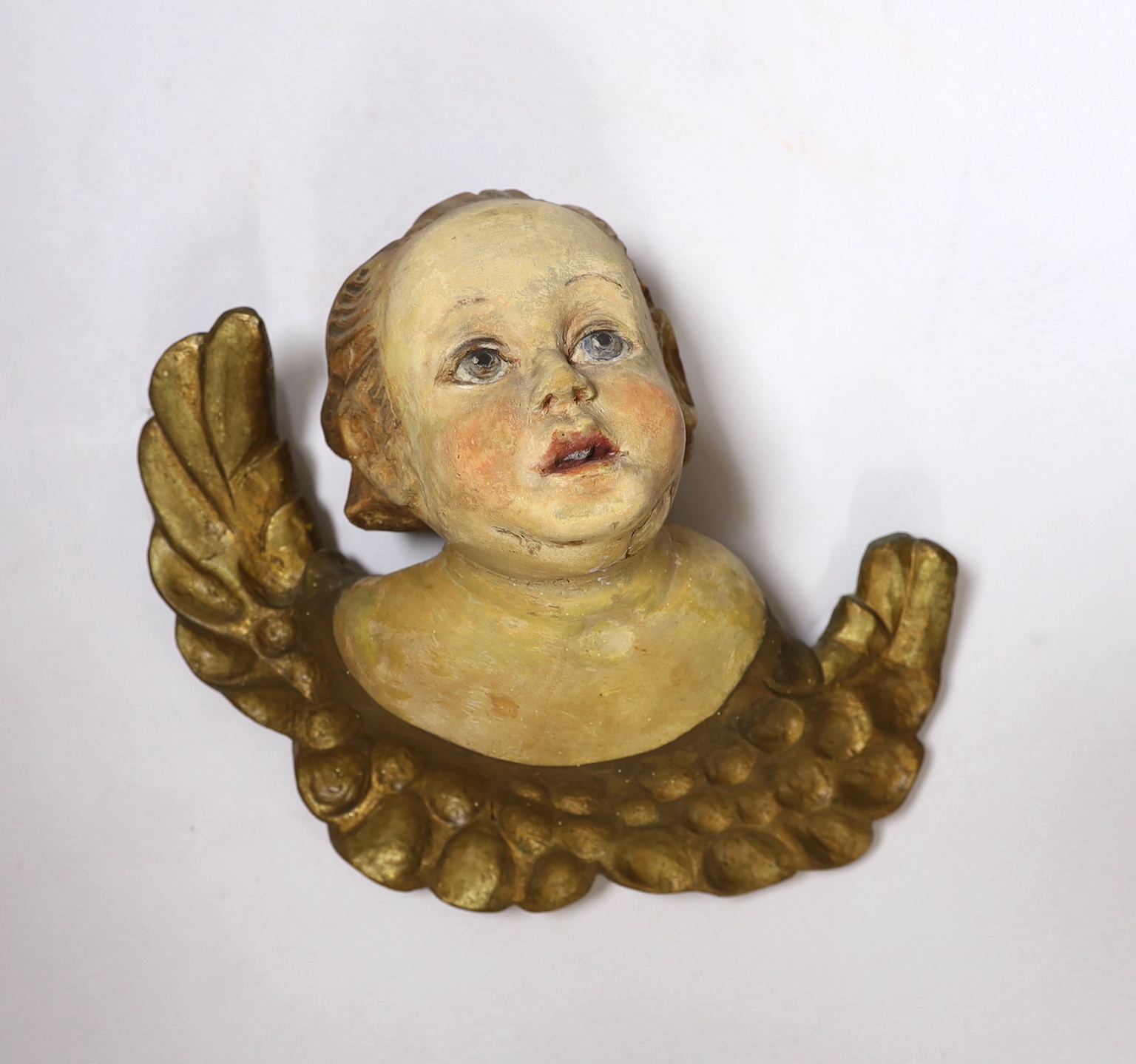 A carved wood gilt and painted cherub wall appliqué, 23cm